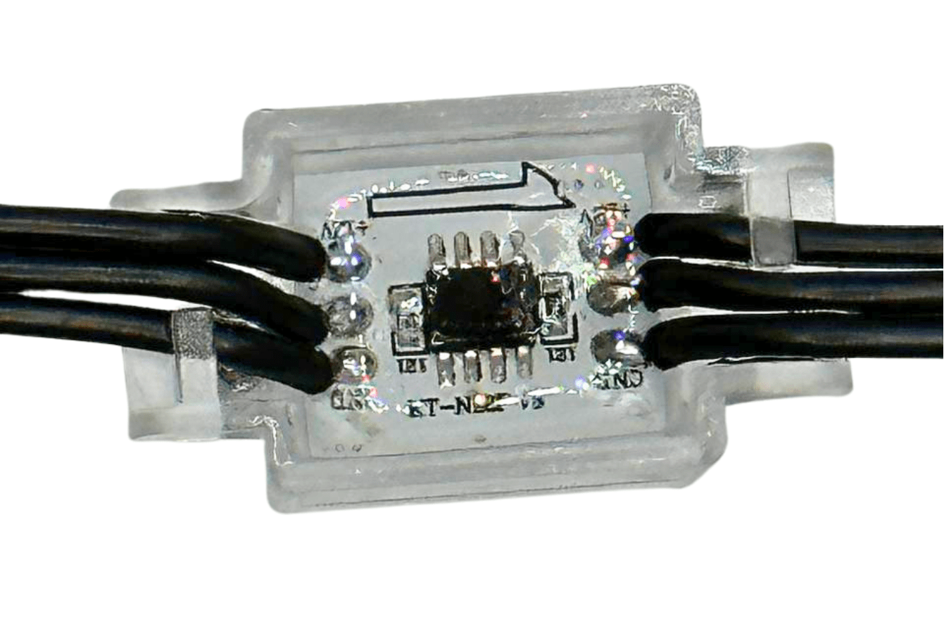 Close-up of a small electronic circuit encased in clear plastic, with black wires connected on both sides. A microchip and several solder points are visible inside the casing.