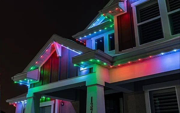 Attached image file A house at night is decorated with multicolored LED lights along the roofline, displaying red, green, and blue hues. The lights illuminate the exterior and give a festive appearance.